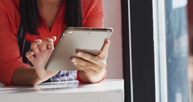 Young woman using tablet near window in casual setting - Download Free Stock Images Pikwizard.com