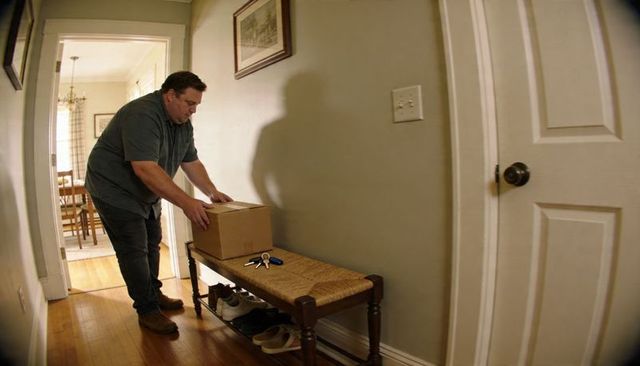 Man placing package on hallway bench near keys and shoes, home entryway delivery moment