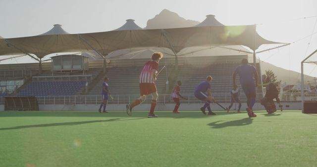 Sunlit Soccer Match on Greenfield with Players and Stadium Seats - Download Free Stock Images Pikwizard.com