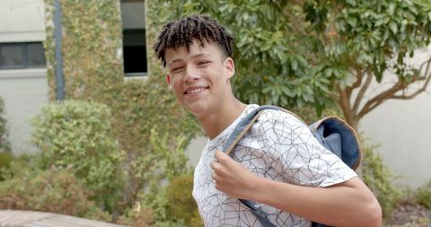 Smiling Teenage Boy Carrying Denim Jacket Outdoors