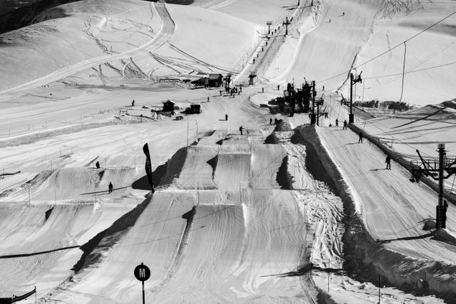 Black and white image of a ski resort showing ski lifts and snowy tracks. Useful for promoting winter sports, ski holidays, and alpine tourism. Also suitable for editorials on winter activities and vacation destinations.