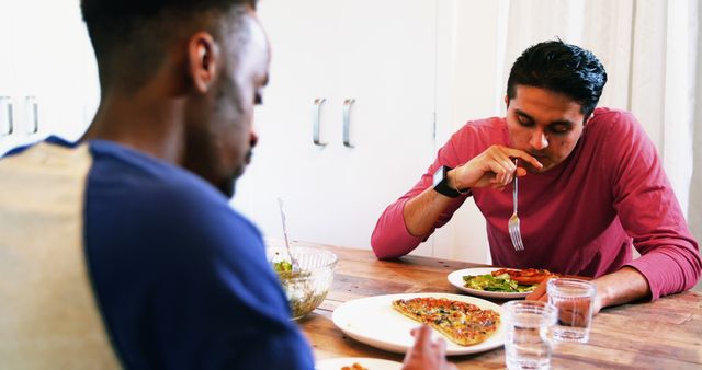Gay couple interacting with each other while having meal at home