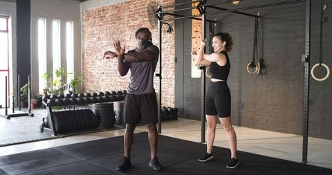 Diverse workout partners performing stretches in modern gym