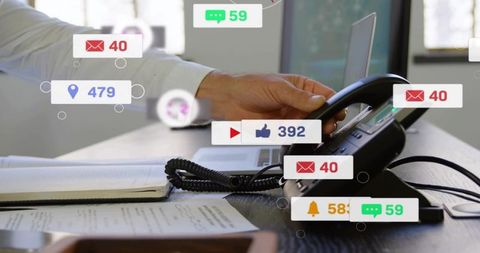 White-shirted man reaching for desk phone among floating notification badges in office