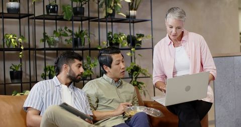 Diverse Team Collaborating in Modern Office Lounge with Plant Shelves