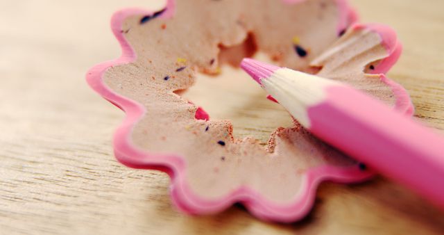 A pink pencil is being sharpened, creating curly shavings on a wooden surface, with copy space - Download Free Stock Photos Pikwizard.com