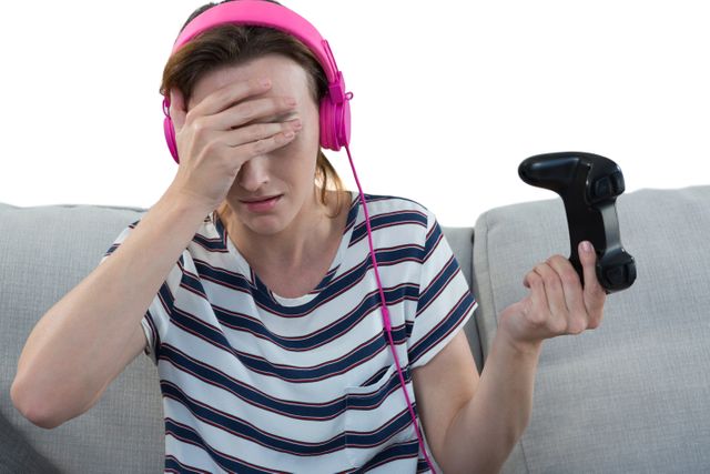 Upset woman in headphones holding joystick against white background