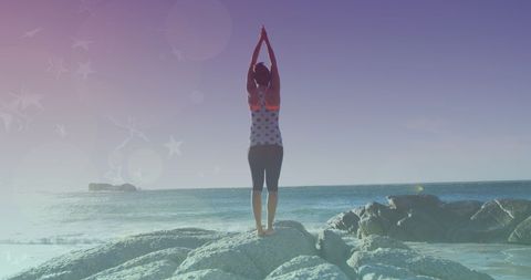 Woman Practicing Yoga on Rocky Beach at Sunset Reflecting Harmony