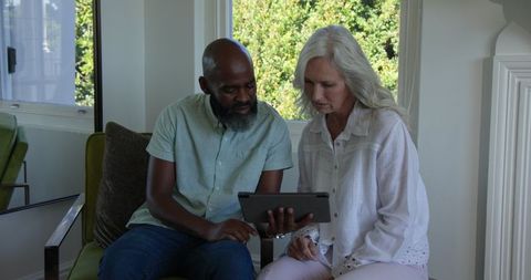 Elderly couple enjoying time with digital tablet at home
