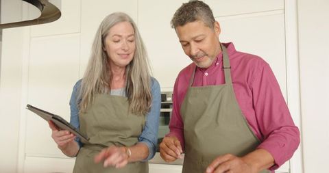 Senior Couple Enjoying Cooking Together Using Tablet