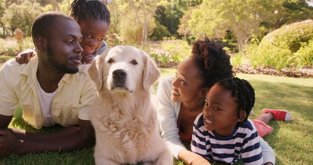 A young African American family enjoys a sunny day outdoors with their golden retriever, with copy space. Their smiles and the relaxed atmosphere reflect a moment of happiness and family bonding.