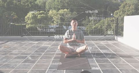 Asian man meditating on rooftop terrace with holographic data overlays for wellness tech