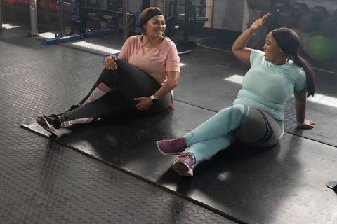 African american women high-fiving after workout on gym mats, fitness partners celebrating