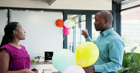 Colleagues decorating office for celebration with balloons