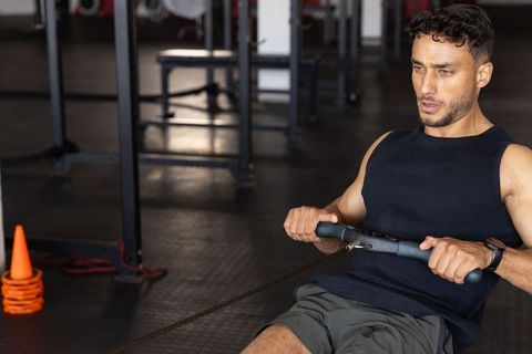 Athletic man utilizing cable row machine for intense workout