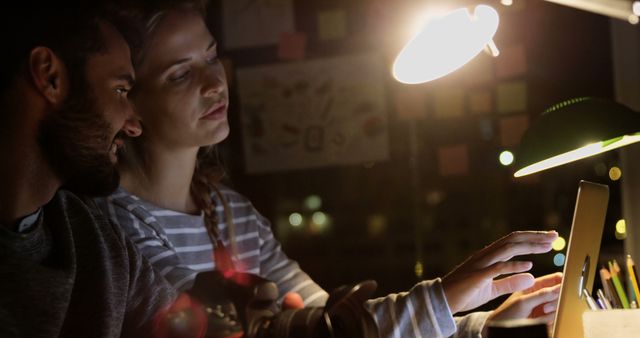 Two young adults are intently collaborating on a tablet in a dim room. - Download Free Stock Photos Pikwizard.com