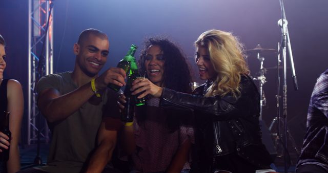 Group of young adults enjoying drinks together at a lively concert. Ideal for promoting events, nightlife experiences, or social gatherings. Great for use in marketing materials for bars, clubs, or beverage companies.