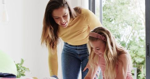 Mother and Daughter Enjoying Packing for Vacation in Cozy Home