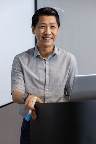 Asian Man Professionally Presenting at Conference Podium
