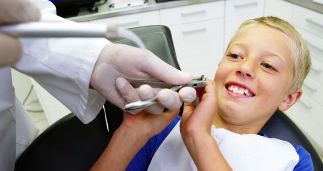 Close-up of young boy smiling during dental checkup with pediatric dentist in clinic. Provides excellent visuals for healthcare services, dental treatment promotions, oral hygiene campaigns, pediatric dentistry advertising, and educational materials on tooth care. Depicts a positive experience at the dentist.