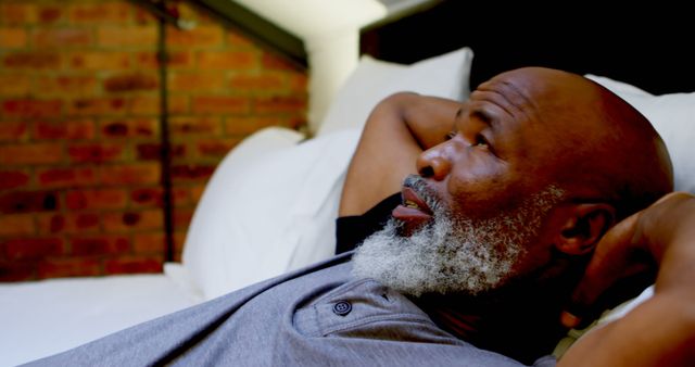 Relaxed African American Man Lying on Bed with Brick Wall Background - Download Free Stock Images Pikwizard.com