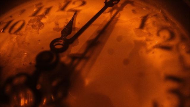 Vintage clock face with metal hands illuminated in warm light