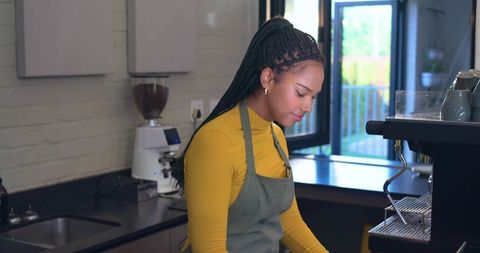 Barista preparing espresso behind counter in bright modern cafe with grinder and machine