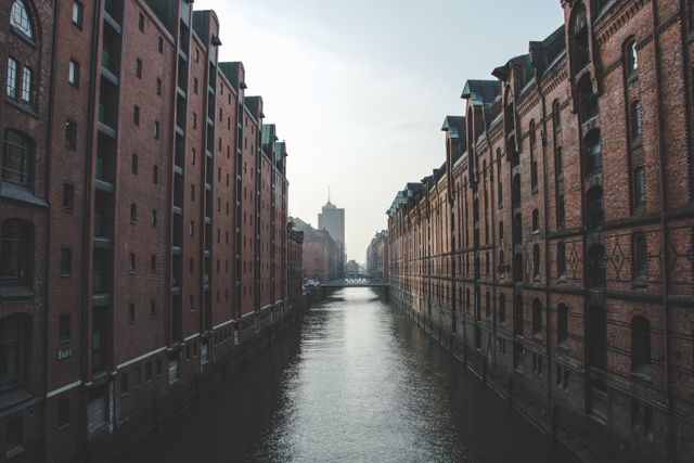 Classic urban architecture scene featuring rows of historic red brick buildings along a calm canal in Hamburg. Perfect for travel blogs, tourism advertisements, architectural studies, and European cityscape collections.