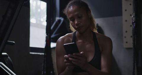 Athletic Woman in Gym Relaxing with Smartphone