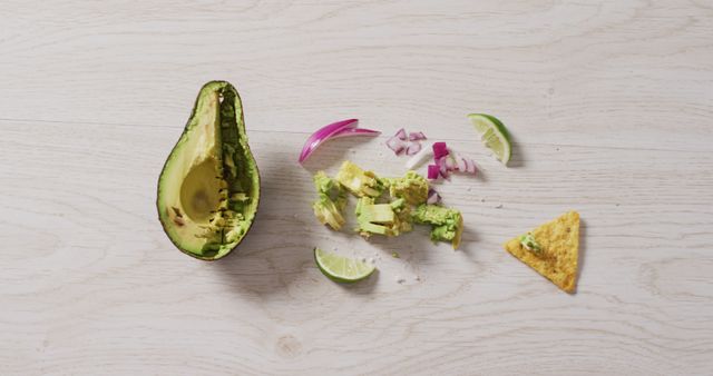 Image of tortilla chip, awocado, onion and lime on a wooden surface. party food and savoury snacks.