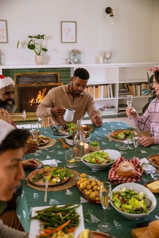 Diverse friends enjoying festive holiday meal with champagne and gravy