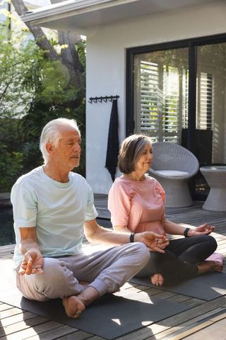 Senior Couple Meditating Outdoors in Tranquil Setting for Wellness