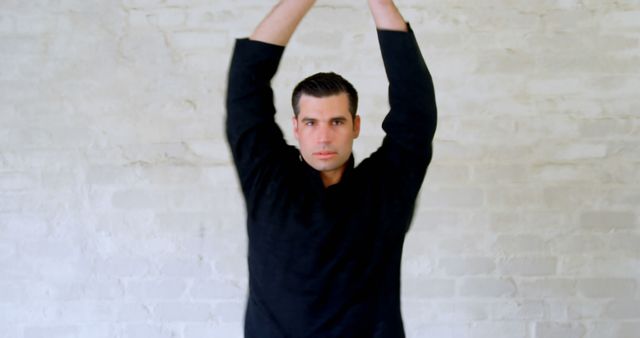 Man in Black Shirt Stretching Against White Brick Wall - Download Free Stock Images Pikwizard.com