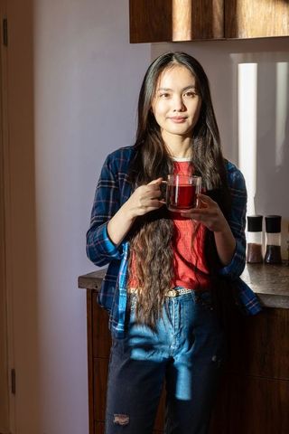 Asian Woman Enjoying Warm Tea in Stylish Rustic Kitchen