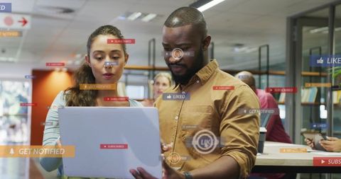 Team collaborating over laptop with social media engagement overlays in coworking office
