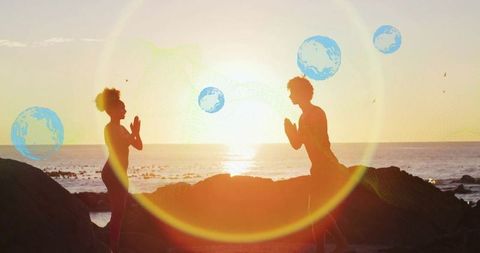 Couple Practicing Yoga on Rocky Shoreline at Sunset