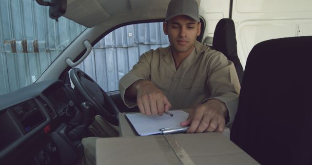 Delivery man in a van checks a package list, with copy space - Download Free Stock Photos Pikwizard.com