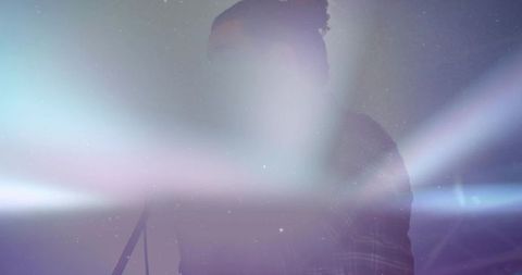 Silhouetted singer performing amid bright lens flares, haze and cosmic light beams