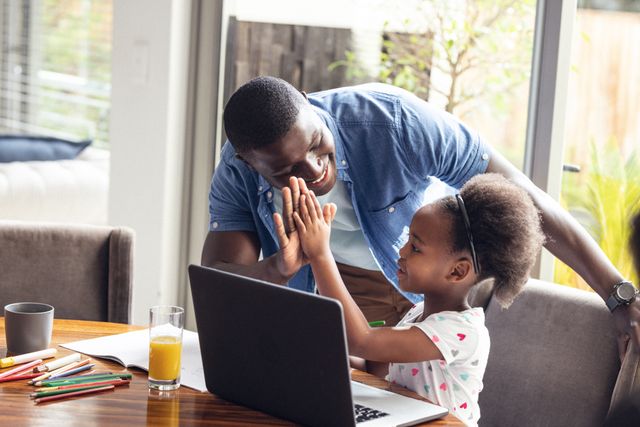 Father and daughter bonding over online learning at home. Ideal for use in educational content, parenting blogs, family lifestyle articles, and advertisements promoting e-learning platforms or family-oriented products.