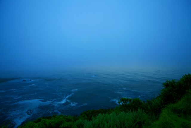 Calm and beautiful coastal morning with misty fog over the quiet ocean. Ideal for use in travel advertisements, website backgrounds, mindfulness and meditation promotions, and nature documentaries.