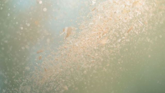 Floating pastel particle swirl macro with shimmering flakes and soft bokeh light