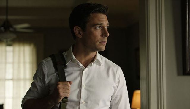Professional man standing in doorway gazing right carrying shoulder bag in warm home