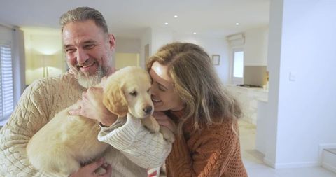 Happy Couple Embracing Golden Retriever Puppy in Cozy Home