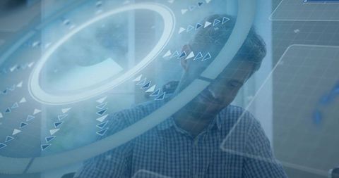 Focused office worker leaning forward working with translucent digital hud overlay at desk