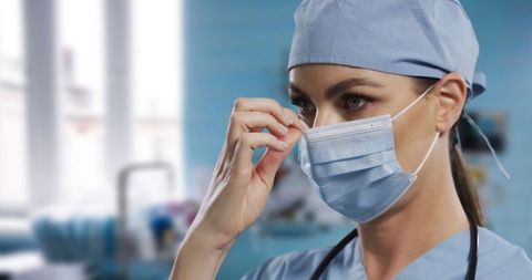 Female Surgeon Adjusting Face Mask in Hospital
