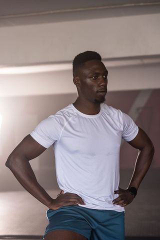 African american athlete standing hands on hips in gym wearing performance tee