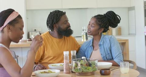 African family sharing relaxed meal and conversation in modern minimalist kitchen