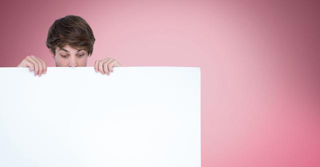 Digital composite of Surprised man looking at blank billboard while standing against pink background