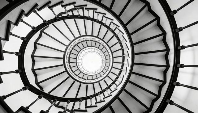 Spiraling black-and-white staircase from below, concentric circular architecture, radial