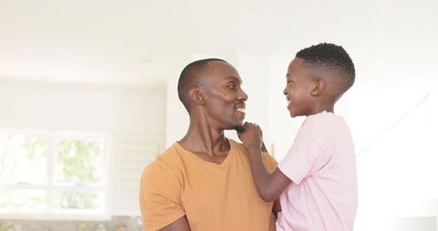 Black father and son sharing joyful moment in sunlit modern home
